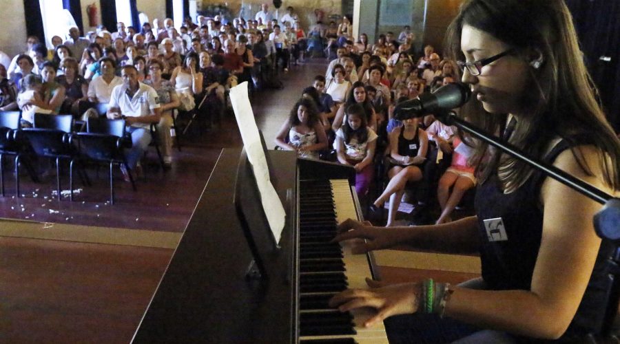 mujer cantando y tocando el piano enfrente de niños y padres